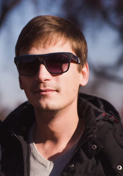 Стильний чоловік з сонцезахисними окулярами позує в осінньому парку — стокове фото