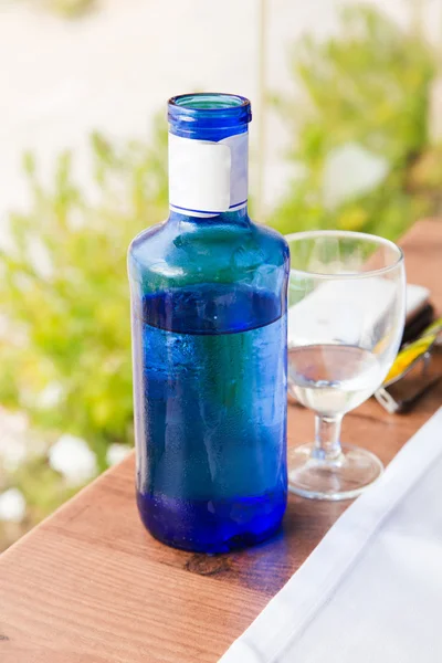 Vidro e garrafa no local na mesa de jantar do restaurante — Fotografia de Stock