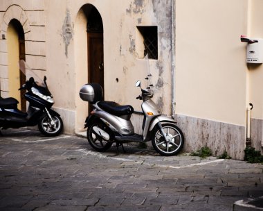 Motorlu scooter bir bina duvarın önünde park etmiş.