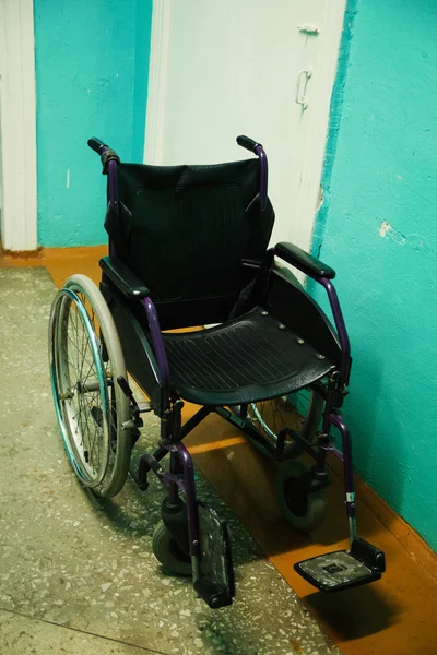 Cadeira de rodas velha em pé em um corredor vazio . — Fotografia de Stock