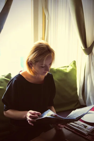 The nice girl chooses what to eat, read restaurant menu — Stock Photo, Image