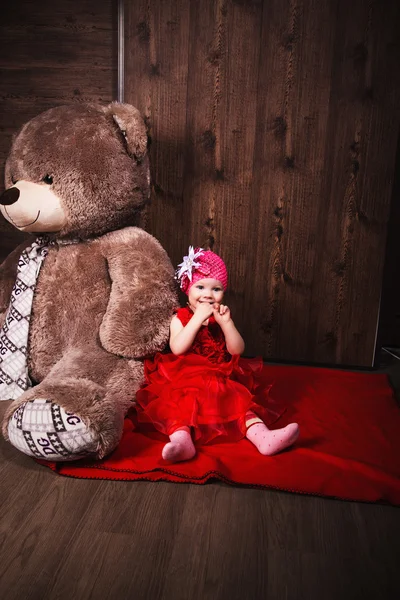 Little cute girl in red dress with big smileTeddy bear. — Stock Photo, Image