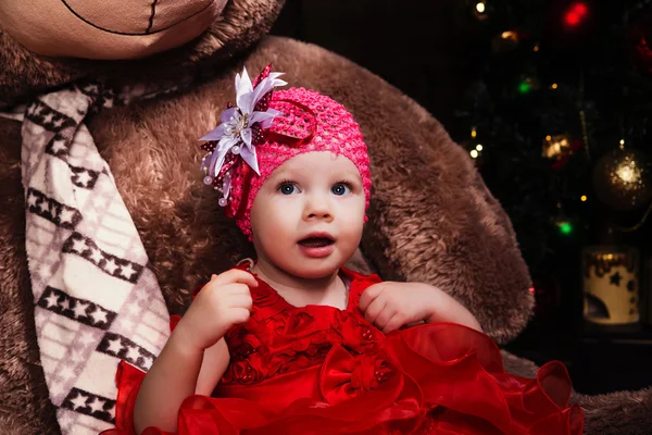 Kis aranyos lány piros ruhában, nagy mosollyal gazdaság mackó. — Stock Fotó