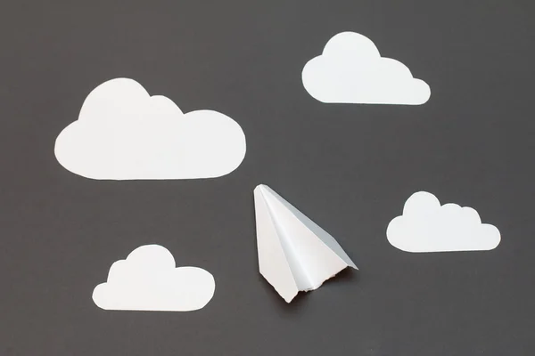 Avion en papier blanc avec nuages sur fond gris — Photo