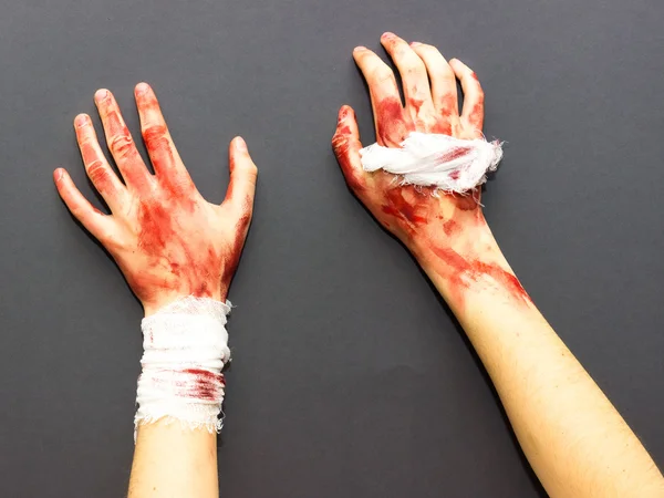 Halloween Tema gri bir arka plan üzerinde kan lekeli bir bandaj ile bağlı kanlı eller