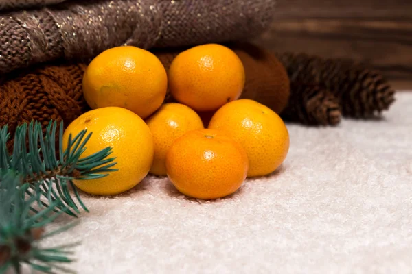 Noel ve yeni yıl mandalina çok renkli kazak, çam kozalakları ve Noel ağacı dalı yanında karda