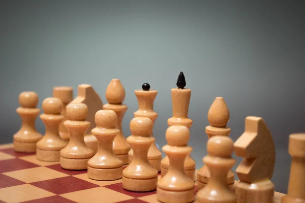 Dřevěná šachovnice a kousky bílé barvy na šedém pozadí — Stock fotografie