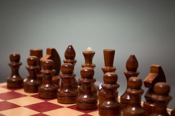 Дерев'яна шахова дошка і шматки чорного кольору на сірому фоні — стокове фото