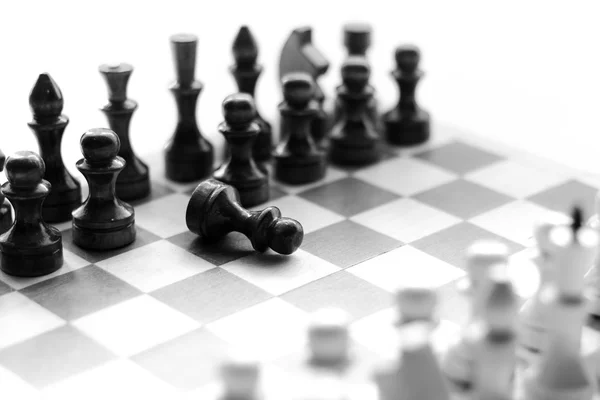 Чорно-біла шахова дошка і шматки, розкидані на дошці на чорно-білому тлі — стокове фото