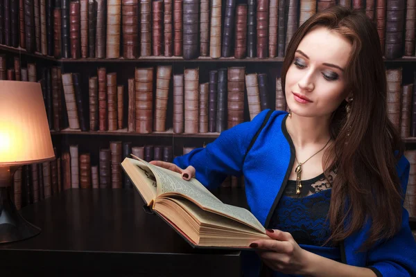 Девушка с книгой на фоне книжных полок, с свободным местом для текста — стоковое фото
