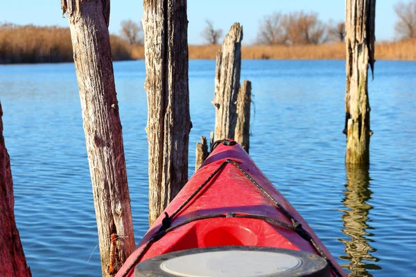 Nehirdeki eski iskelenin sütunlarının yanındaki kırmızı kano yayı. Soğuk mevsimde kano.
