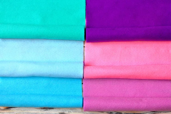 Beyaz ahşap arka planda parlak renkli keçeli kumaş ruloları