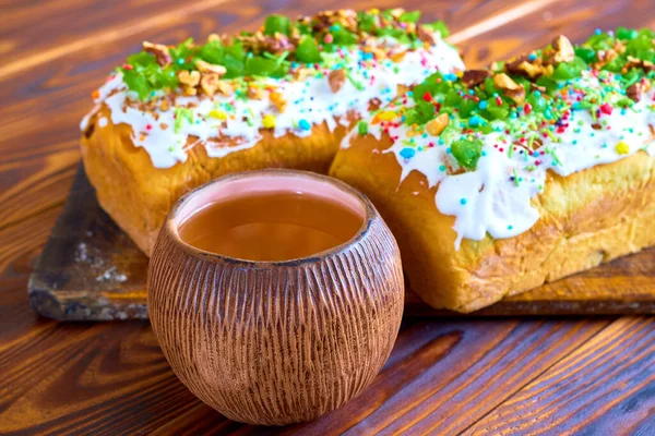 Paskalya tatlı ekmeği Ortodoks Kulich, Paska. Beyaz kremayla süslenmiş iki dikdörtgen pasta ve şeker parçacıkları ve yeşil çayla süslenmiş bir kase.