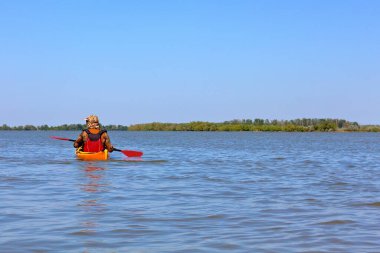 Adam Tuna nehrinde sarı bir kano sürüyor. Yaz kayağı
