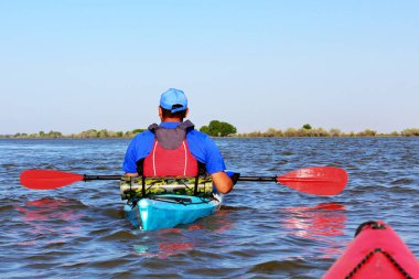 Yazın Tuna nehrinde kırmızı bir kano yüzdüren bir adam. Kanodan görünüm