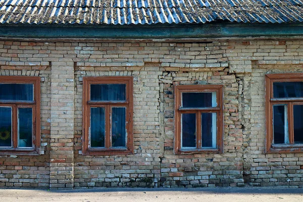 Facade of the old house in emergency condition of red brick with four windows in wood frames