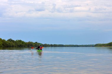 Tuna nehrinde yeşil bir kanoyla kürek çeken bir adam. Su turizmi. Kano..
