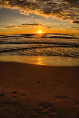 Bulutlu bir günde güzel bir sahilden doğan güneş.