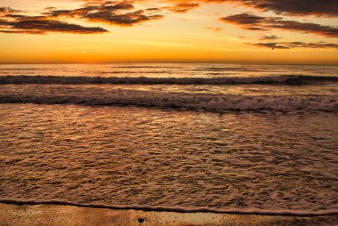 Bulutlu bir günde güzel bir sahilden doğan güneş.