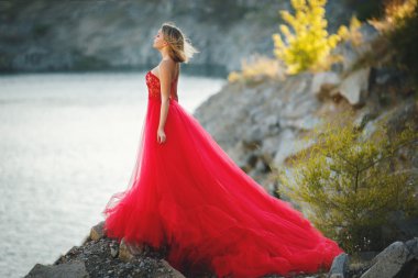 Doğa üzerinde uzun Kırmızı elbiseli sarışın kız