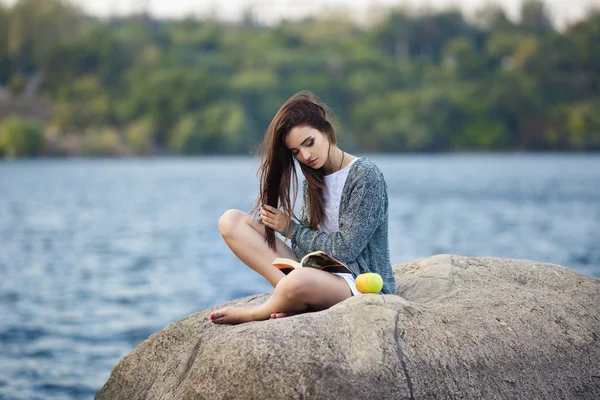 Vacker flicka med apple läser en bok — Stockfoto