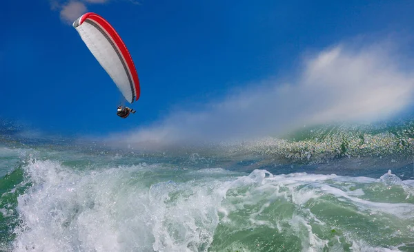 Fırtınalı bir denizin üzerinde gökyüzünde bir paraglider. Gökyüzünde bulutlar, denizde dalgalar, deniz dalgaları üzerinde paraşüt altında uçan bir sporcunun görüntüsü. 