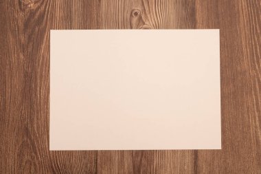Tahta yüzey üzerinde bej bej bir kağıt ile düz bir şekilde yatıyordu. Minimalist modeller, davetiyeler, metin kaplamaları veya markalaşma tasarımı için mükemmel.