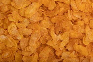 Altın gevrek mısır gevreğinin detaylı yakın çekim dokusu. Kahvaltı, sağlıklı yiyecekler, ambalaj tasarımı ve beslenme kavramları için mükemmel..