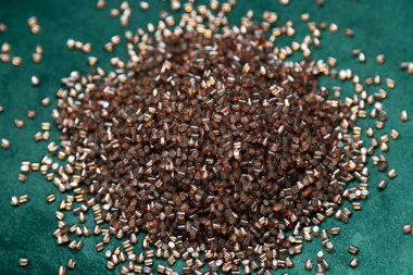 Yeşil desenli arka planda yarı şeffaf kahverengi polimer granüller fotoğraflandı. Hammadde işleme, geri dönüşüm ve kimyasal imalatı ile ilgili konular için mükemmel..