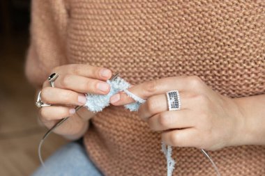Yumuşak beyaz bir iplik parçası ören, dokuyu, zanaatı ve sıcaklığı vurgulayan örgü iğneleriyle ören, yakın çekim yapan bir kadın. Yüksek kalite fotoğraf