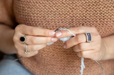 Ayrıntılı makro stil görüntü örgü iğnelerine sarılı beyaz iplik ve dikiş oluşturan eller gösteriyor. Örgü iğneleriyle ören bir kadın, yakın çekim. Yüksek kalite fotoğraf