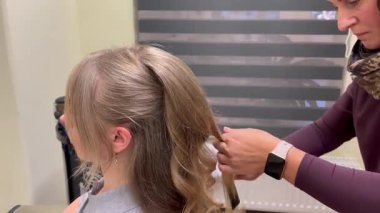 Kadın saçı şekillendirirken tarakla saç şekillendiren profesyonel bir kuaför. Güzellik salonu kuaförlüğü ve bakım konsepti.