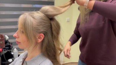 Şık bir saç stili için saç kıvırırken profesyonel saç şekillendirme sürecinin yakın görüntüsü. Festivaller ve özel durumlar için güzellik salonu hizmeti.