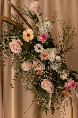 Pastel güller ve okaliptüslü doğal ışıkta zarif bir çiçek aranjmanı.