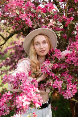 Çiçekli bahçede huzurlu bir kadın taze bahar atmosferinin tadını çıkarıyor. Yüksek kalite fotoğraf