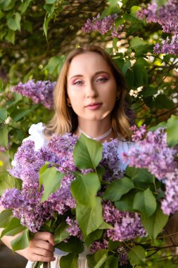 Bahar bahçesinde çiçek açan leylak buketi tutan güzel bir kadın. Yüksek kalite fotoğraf