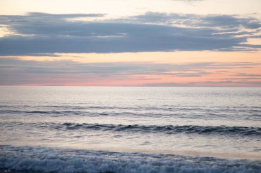 Yumuşak dalgalar ve ılık akşam parıltılarıyla rüya gibi sahil günbatımı. Yüksek kalite fotoğraf