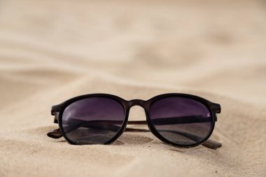 Sıcak kumsalda dinlenen siyah güneş gözlükleri deniz seyahati modunda. Yüksek kalite fotoğraf