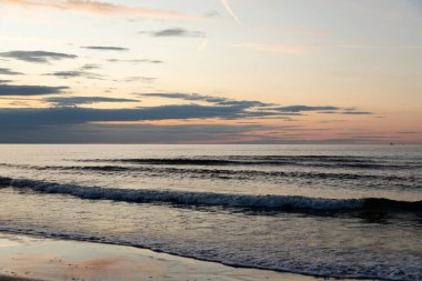 Dalgalar ve sıcacık renklerle rahatlatıcı bir plaj akşamı. Yüksek kalite fotoğraf