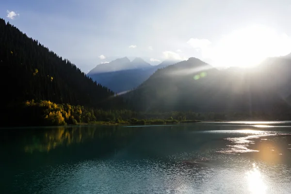 Raios de sol brilhantes sobre lago de montanha — Fotografia de Stock