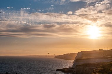 Akşamüstü güneşli ve bulutlu gökyüzünde görünen kayalıklar, Doğu Sussex, İngiltere.