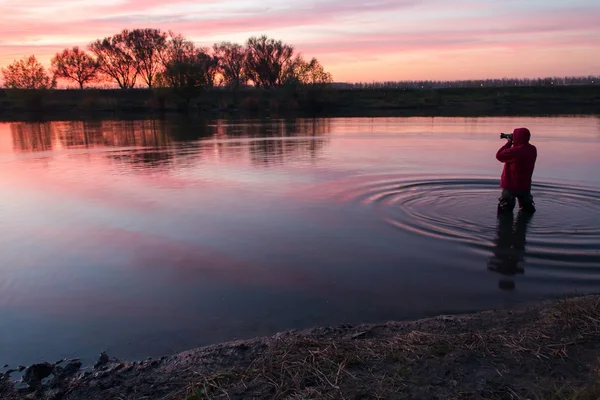 The man costs in the small river and admires a decline. — Stock Photo, Image