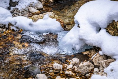 Kış dağlarında karlı kayalık yüzeyde akan su