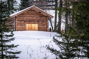 Ormandaki dağlık alanda karla kaplı ahşap kulübe..