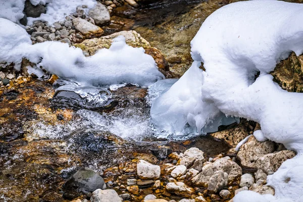 Kış dağlarında karlı kayalık yüzeyde akan su