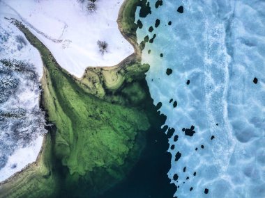 İtalya 'daki Predil Gölü' nün yeşil sularının yakınındaki çam ağaçları ile karla kaplı hava manzarası