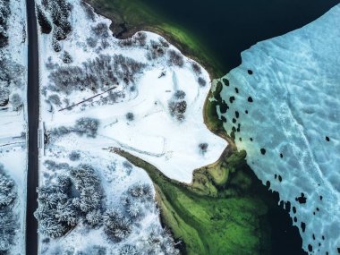 İtalya 'daki Predil Gölü' nün yeşil sularının yakınındaki çam ağaçları ile karla kaplı hava manzarası