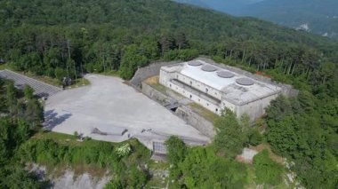 Ağaçlarla çevrili büyük beton binanın havadan görünüşü