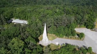 Yüksek anıt yemyeşil ağaçlarla çevrili.