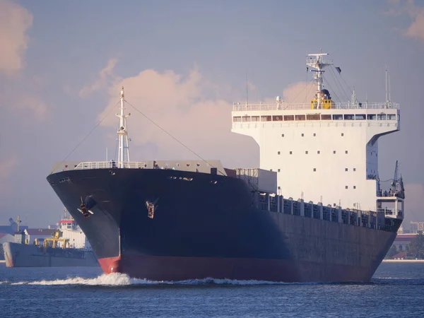 The big cargo ship was empty on the river at evening.